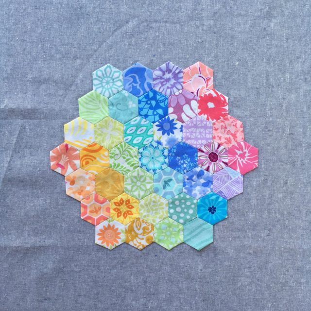 An English paper pieced Kate Spain rainbow hexagon on Essex Linen by BlossomHeartQuilts.com