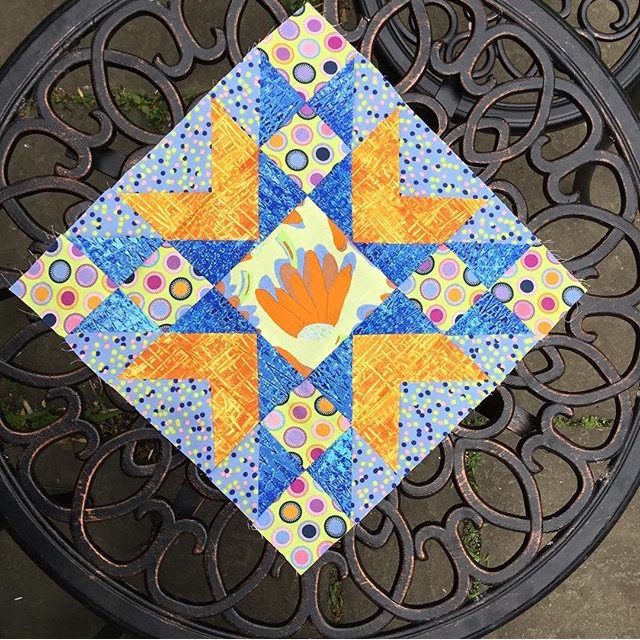 An orange and blue Double Star quilt block from the free pattern at BlossomHeartQuilts.com