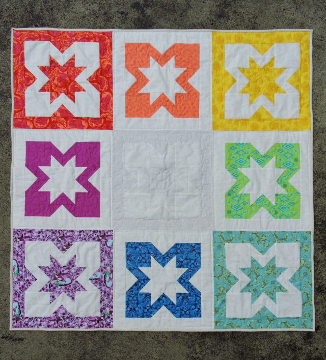 A Tula Pink rainbow quilt using the Geode pattern by BlossomHeartQuilts.com