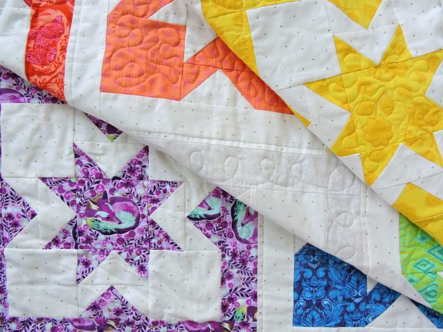 Baby Geode quilt using a rainbow of Tula Pink fabric by BlossomHeartQuilts.com