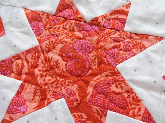 Free motion quilting outlining Tula Pink fabric on Geode quilt by BlossomHeartQuilts.com