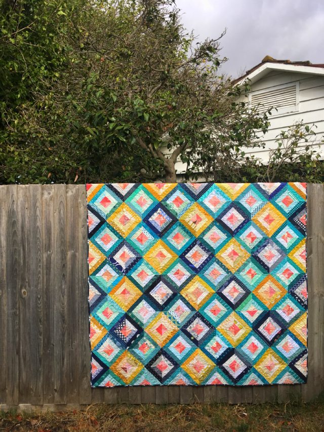 Scrap quilt using Treasure Hunt quilt block tutorial in navy, mustard, teal and coral by BlossomHeartQuilts.com