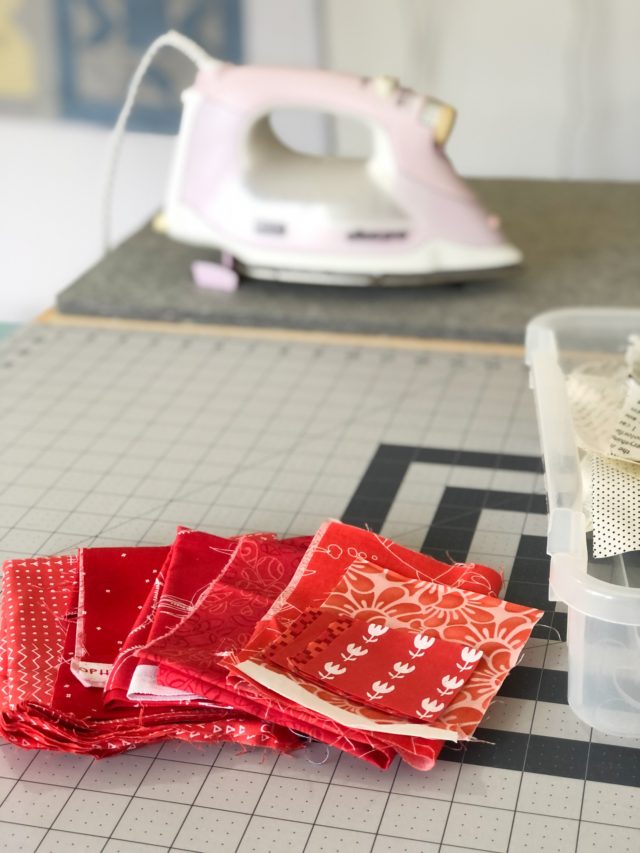 Red fabric scraps sitting on a cutting mat